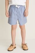Young child wearing Spanish Slate Le Club Short, showcasing a classic, effortless style with a small white bow and tan boat shoes for a fun, high-end look.