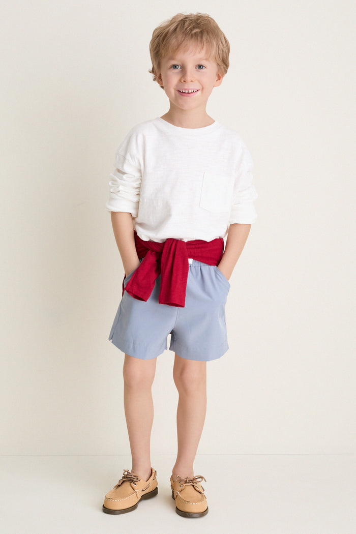 Young boy models the Spanish Slate Le Club Short, showcasing a classic, effortless look with lightweight, quick-drying fabric, perfect for fun, high-end summer adventures.