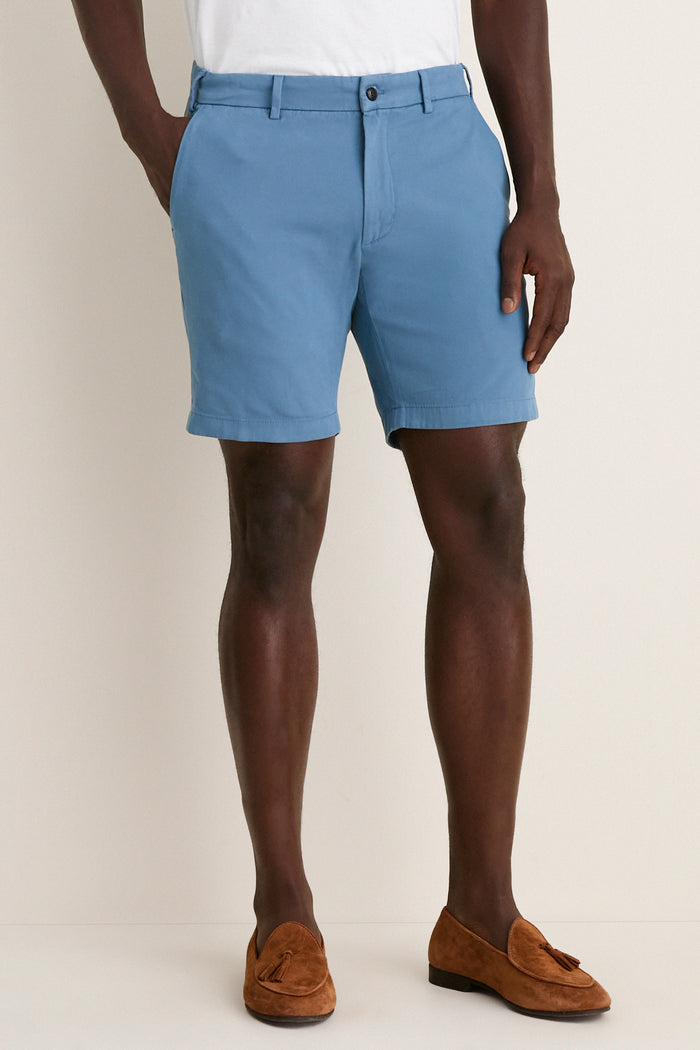 Classic Storm Andrews Flat-Front Short in light blue, worn with white T-shirt and brown loafers. Effortless style for fun, high-end warm-weather adventures.