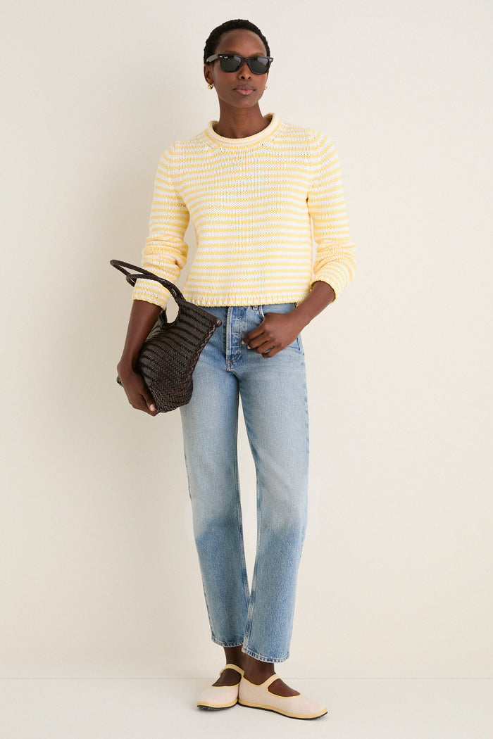 A person wearing the Sunshine and Cream Fine Stripe Mini Marina Sweater with light jeans and chic accessories, embodying a classic, effortless, high-end, and fun spring look.