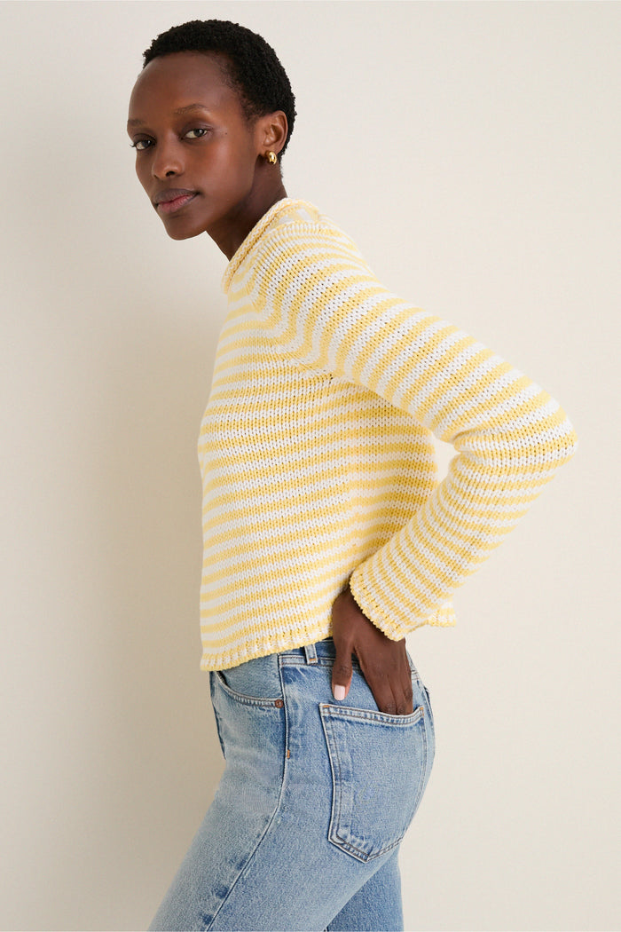 Person wearing the classic Sunshine and Cream Fine Stripe Mini Marina Sweater, showcasing its effortless, high-end style with a roll-neck and relaxed fit, paired with blue jeans.