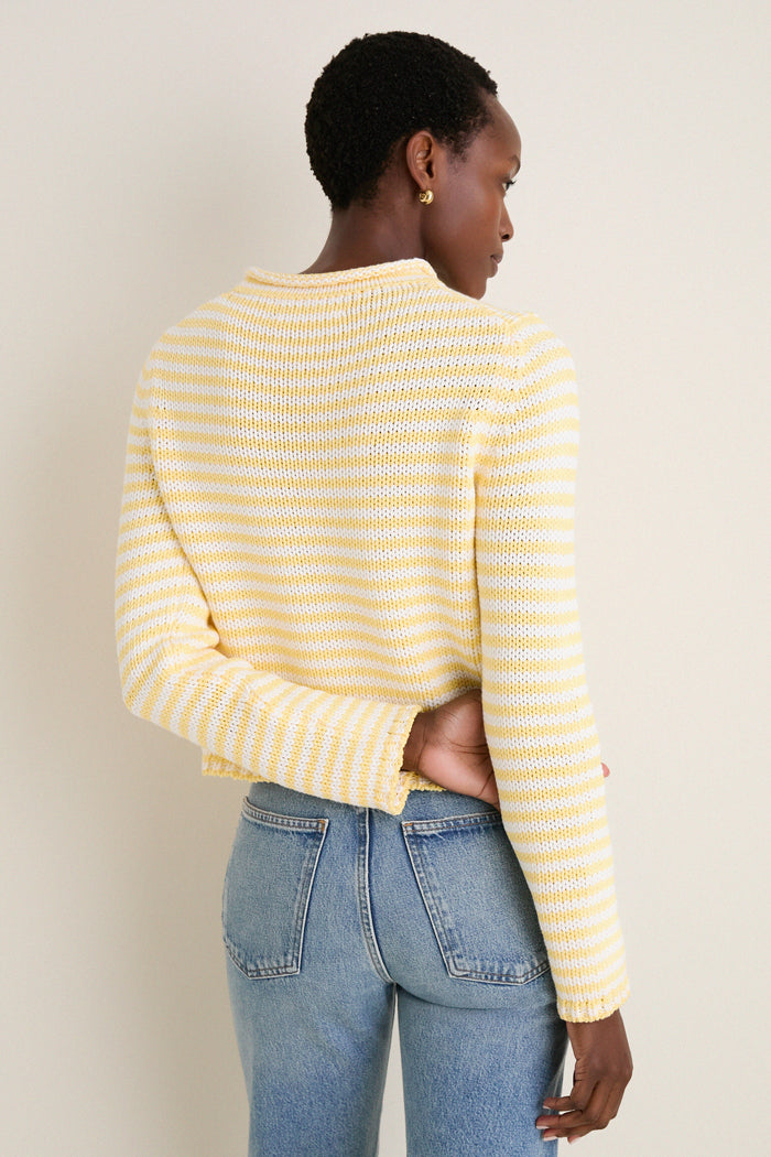 Person wearing the Sunshine and Cream Fine Stripe Mini Marina Sweater, showcasing its classic roll-neck and slim sleeves for an effortless, high-end look paired with light-wash jeans.