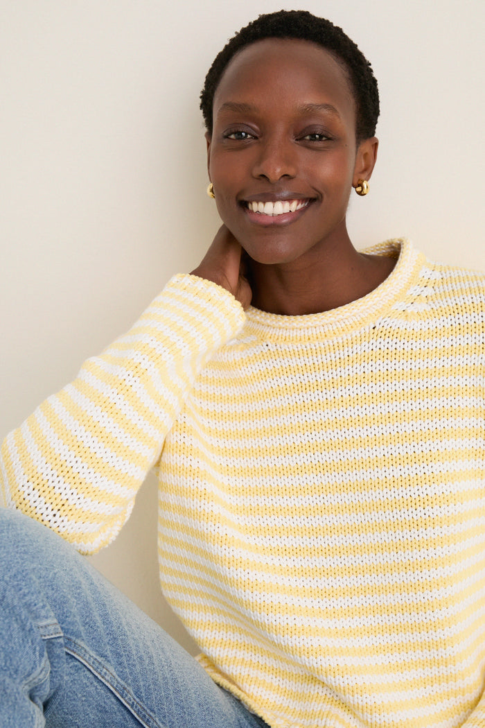 Smiling woman in a classic, effortless Sunshine and Cream Fine Stripe Mini Marina Sweater with a roll-neck, showcasing high-end, fun style against a neutral background.