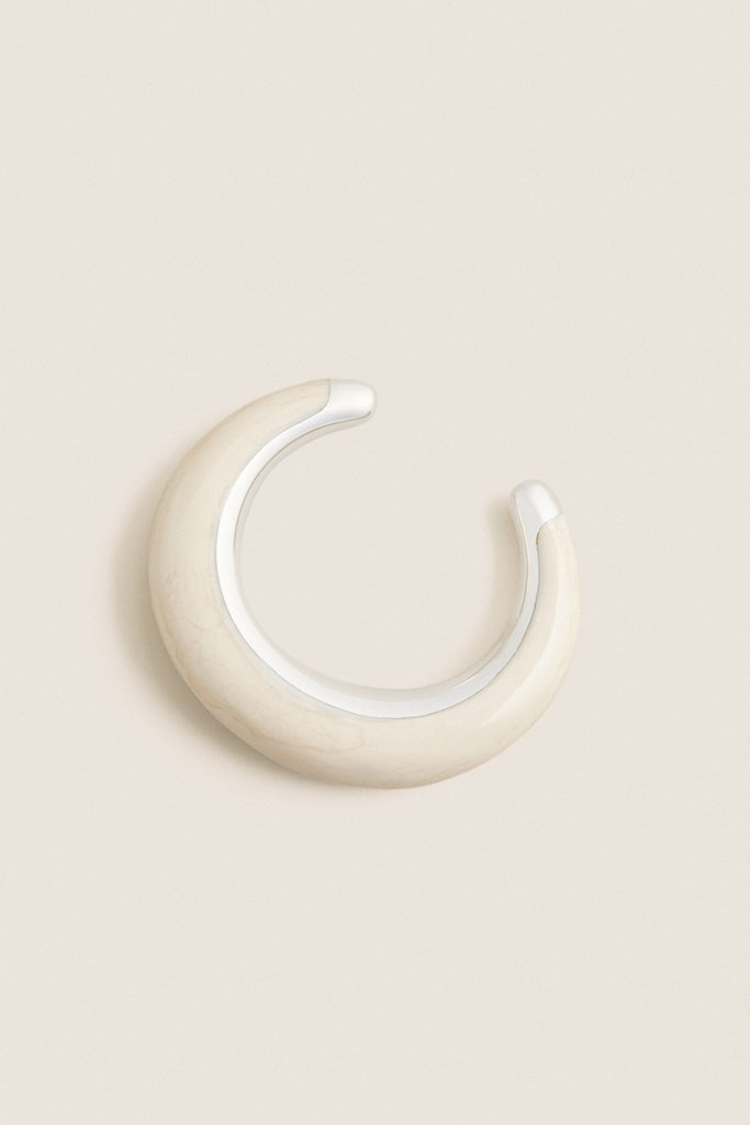 Swirl Chalk Crescent Cuff: A classic, high-end ear cuff with a glossy cream enamel finish and silver-tone accents, offering an effortless, fun touch to any outfit.