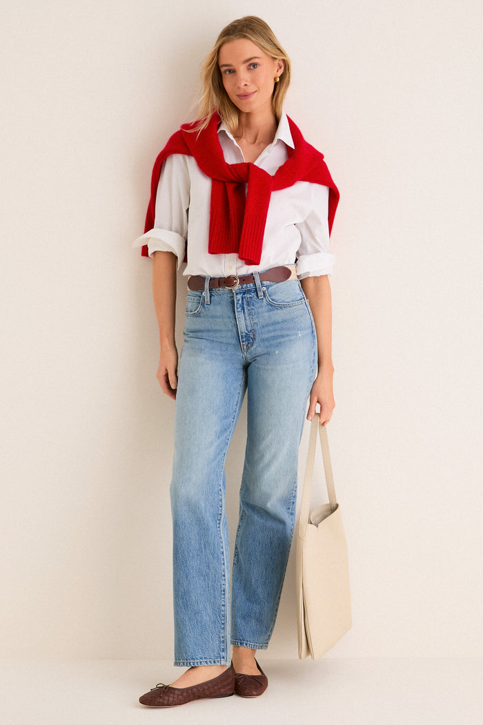 Young woman in preppy outfit showcases a classic, effortless style, wearing a Tan and White Woven Strap Belt with polished gold buckle over light-wash jeans.