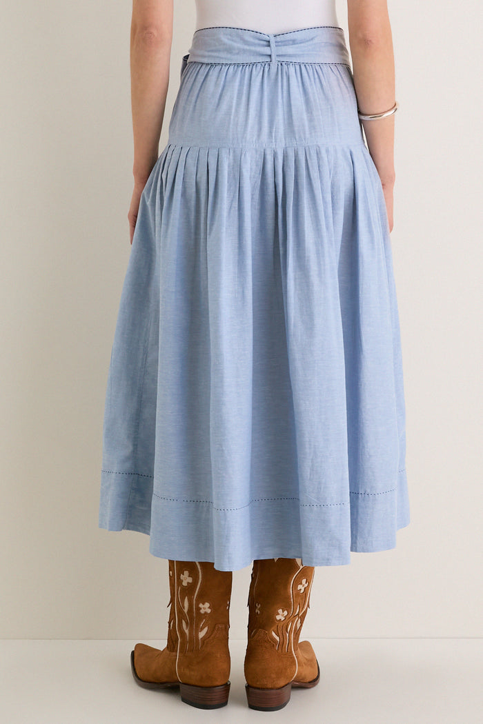 The Chambray Embroidered Highland Skirt paired with cowboy boots exudes classic, effortless style, blending fun western inspiration with high-end, refined details like gentle pleats and floral embroidery.