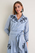 Young woman in The Chambray Embroidered Western Shirt featuring classic floral embroidery, pleated skirt, and relaxed fit, embodying effortless high-end style and fun confidence.