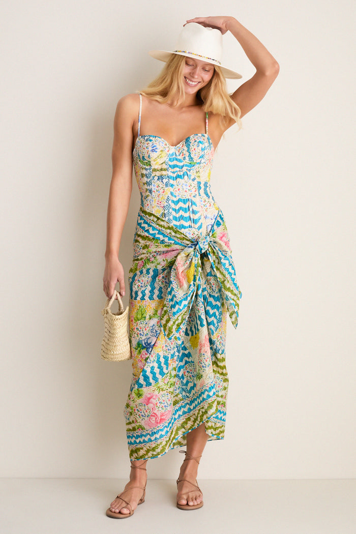 Person in a classic, colorful sundress and sandals, wearing the White and Multi Charlotte Traveler Hat. The hat features playful beaded accents for an effortless, high-end summer look.