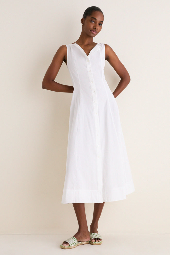 A slim woman models a White Cotton Boat Neck Dress, exuding effortless elegance with its classic sleeveless design, ideal for high-end, fun, warm-weather styling.