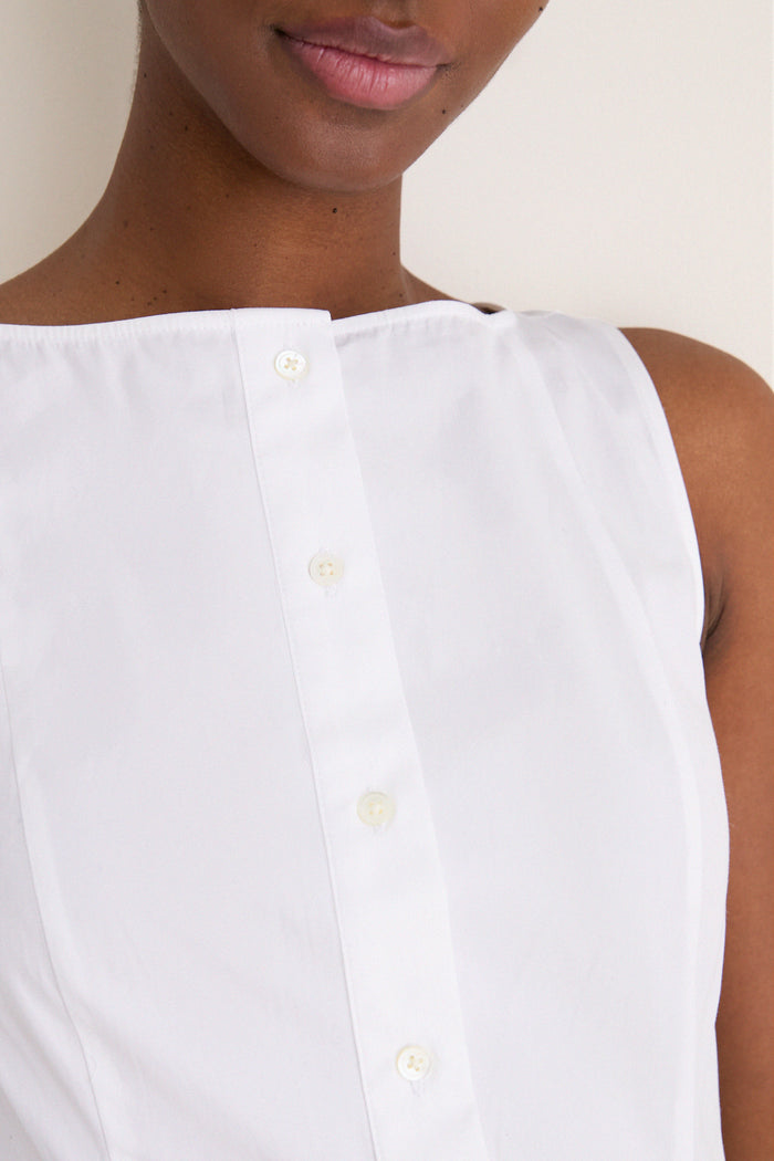 Close-up of a person wearing a classic, sleeveless white cotton boat neck dress, showcasing its effortless, high-end design with a fun, relaxed fit.