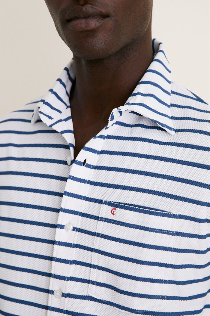 Classic and effortless, the White Performance Pique Knit Button Down features navy stripes, a chest pocket with a red logo, and an open collar for a high-end, fun look.