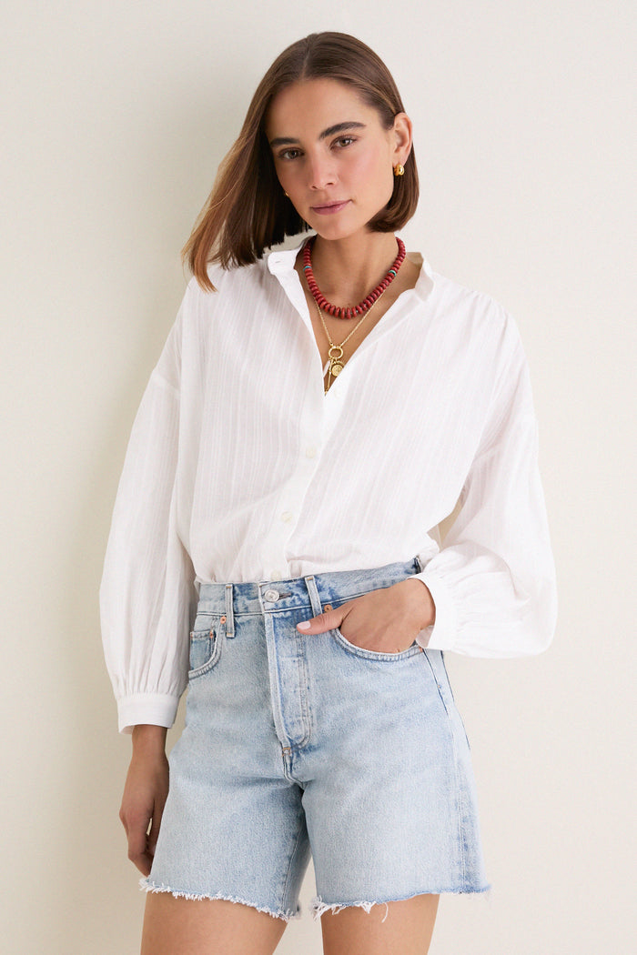 White Shadow Stripe Juliette Button Down: Classic, effortless blouse with gathered sleeves, asymmetrical hem, tucked into light-wash shorts for a fun, high-end look.