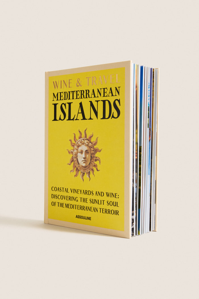 Hardcover book titled Wine & Travel Mediterranean Islands by Assouline, featuring a classic sun-face motif, promises an effortless, fun journey through high-end Mediterranean wine culture.
