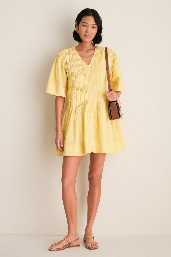 Yellow Alberte Solid Mini Dress: classic and effortless, featuring a V-neck, pintuck details, relaxed fit, and playful flared skirt, styled with chic gold sandals and a leather crossbody.