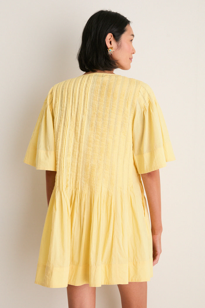 Yellow Alberte Solid Mini Dress featuring pintuck detailing and a gathered skirt, worn by a model with a bob haircut, embodies classic, effortless, and high-end style.