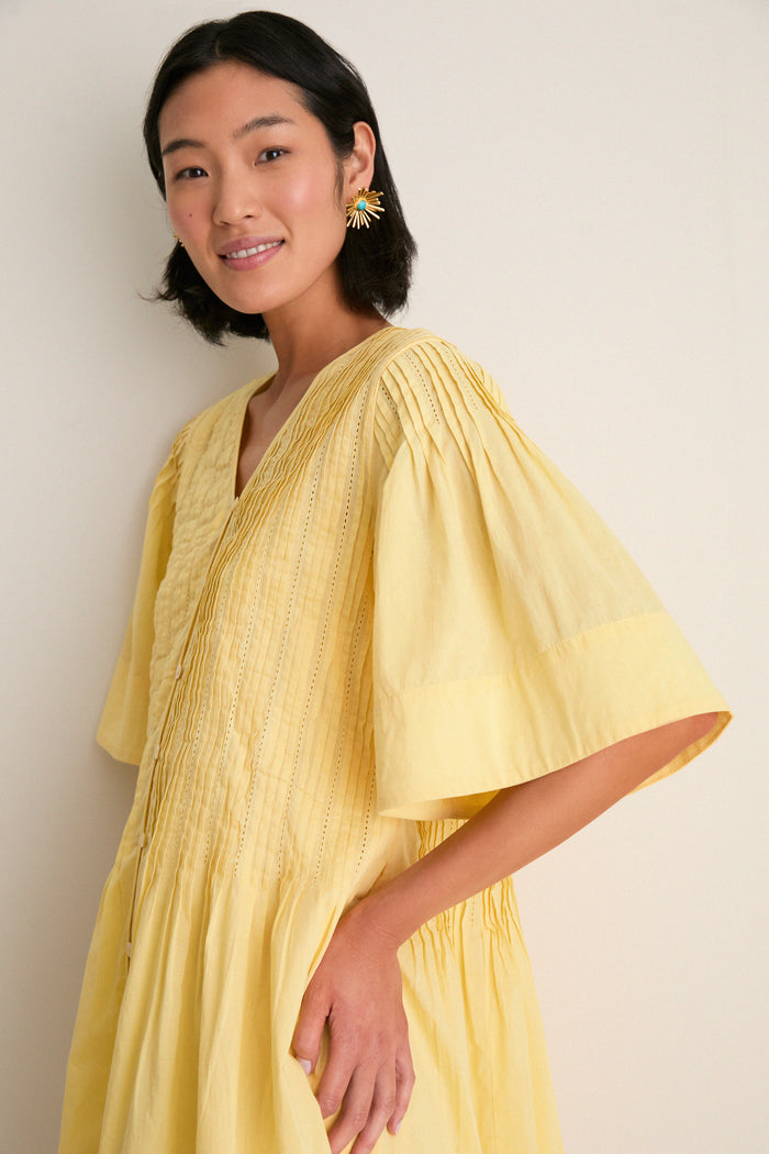 Young woman in a classic, effortless Yellow Alberte Solid Mini Dress, featuring pintuck pleating and elbow-length sleeves, exuding fun and high-end charm.