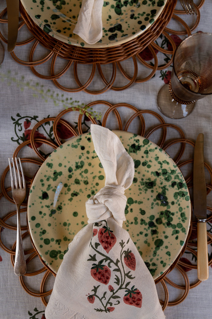 Classic and effortless table setting featuring the Yellow and Verde Splatter Dinner Plate, with a fun strawberry napkin and high-end vintage-style cutlery.